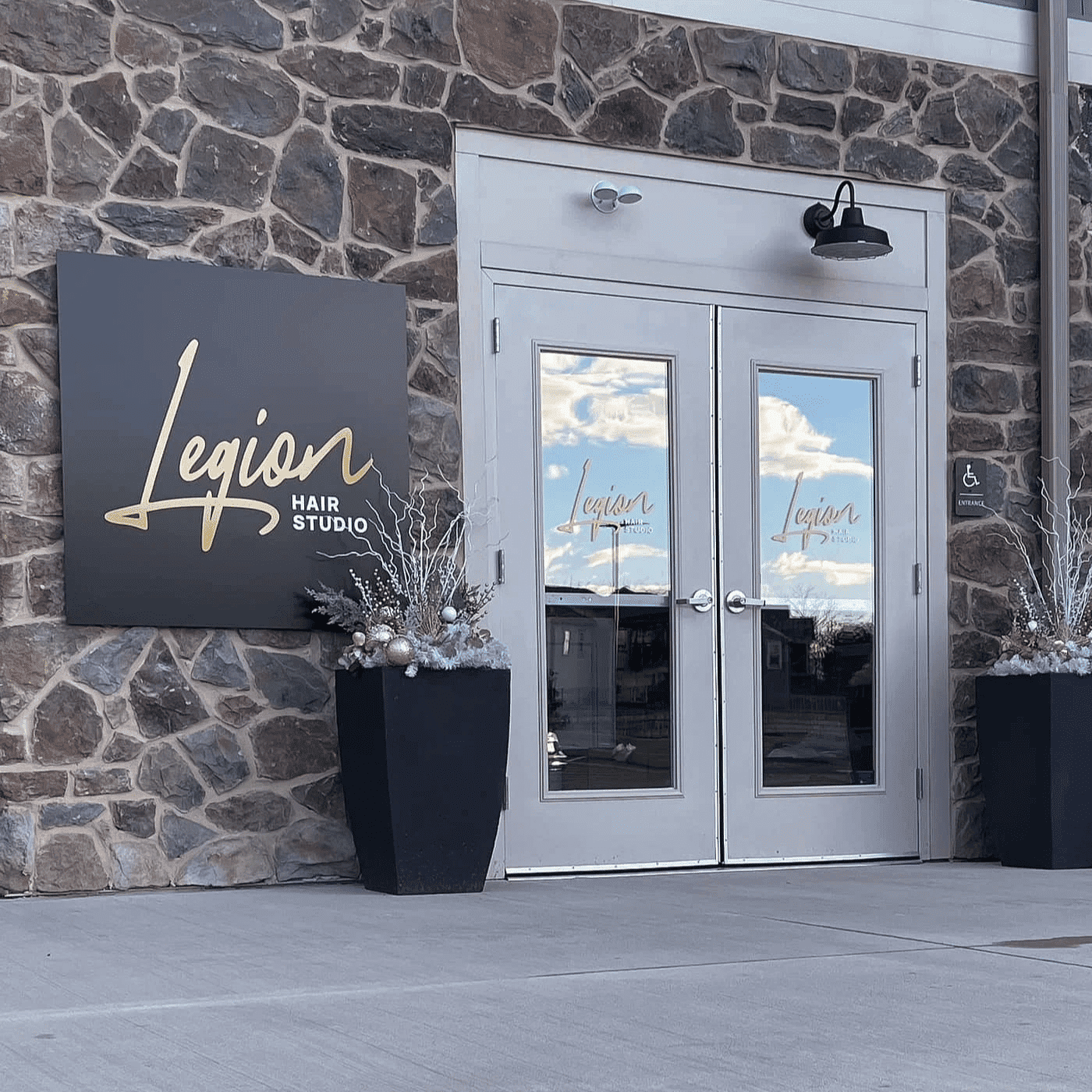 Entrance of Legion Hair Studio with large sign and holiday decorations by the door.